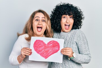 Poster - Middle east mother and daughter holding paper with heart draw celebrating crazy and amazed for success with open eyes screaming excited.