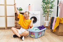 Young Blonde Girl Doing Laundry Listening To Music At Home.