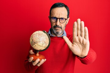 Poster - Middle age hispanic man holding vintage world ball with open hand doing stop sign with serious and confident expression, defense gesture