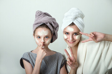 Two girls playing with cosmetic SPA mask on their faces. Little girl and young woman enjoy spa treatments. SPA and wellness