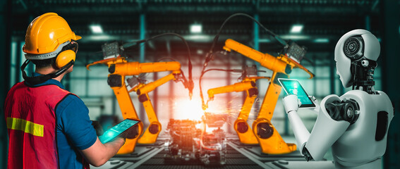 Mechanized industry robot and human worker working together in future factory . Concept of artificial intelligence for industrial revolution and automation manufacturing process .