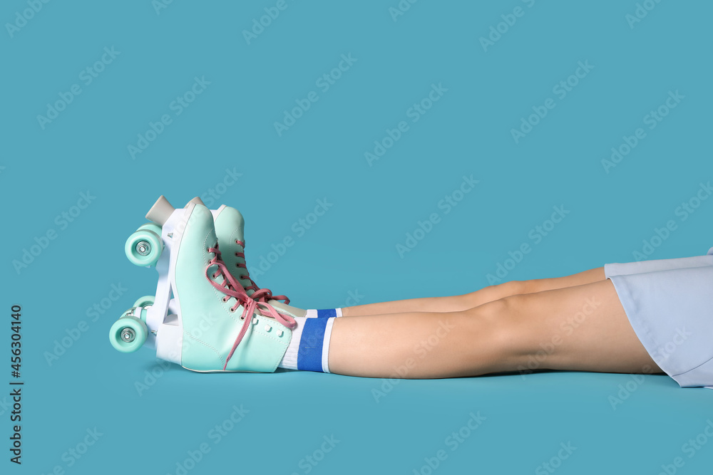 Young woman in roller skates on color background
