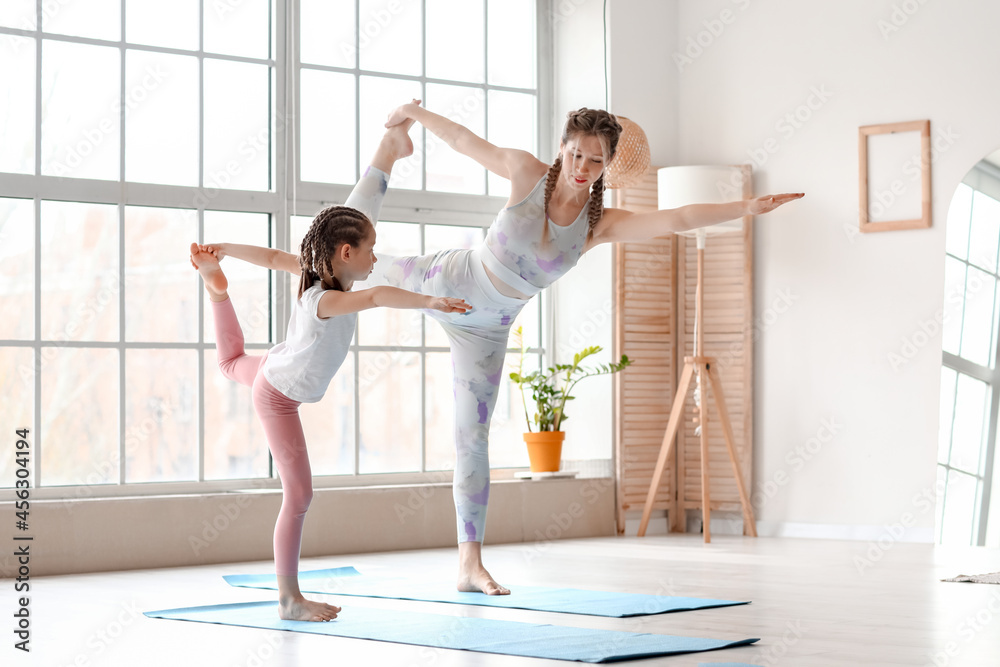 Little girl with her mother practicing yoga at home