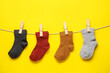 © Pixel-Shot - Different baby socks hanging on rope against color background