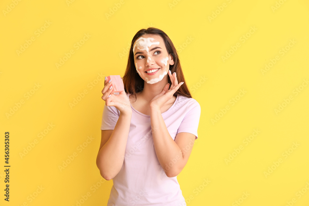 Beautiful young woman with soap on color background