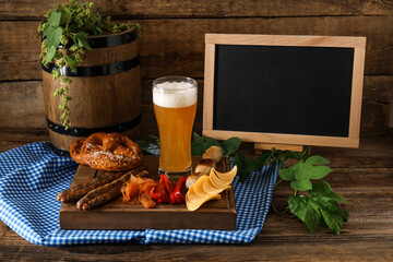 Composition with fresh beer and blank chalkboard on wooden background. Oktoberfest celebration