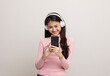 © Chanakon - Beautiful young asian women choose song and play music from smartphone connection with wireless headphone having fun in home. Teenage girl listen to the music enjoy relaxing on isolated background.