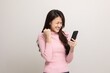 © Chanakon - Pretty young asian woman using smartphone standing on isolated white background feeling happy. Shopping online payment with mobile phone. Excited and surprised female holding cellphone.