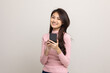 © Chanakon - Pretty young asian woman using smartphone standing on isolated white background feeling happy. Shopping online payment with mobile phone. Excited and surprised female holding cellphone.