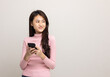 © Chanakon - Pretty young asian woman using smartphone standing on isolated white background feeling happy looking blank space. Shopping online payment with mobile phone. Excited female holding cellphone.