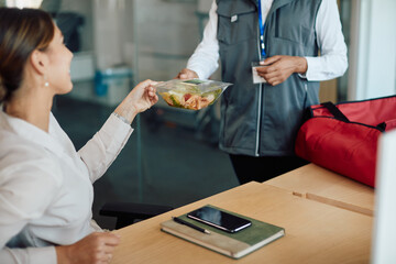 Wall Mural - Close-up of businesswoman receives food delivery while working in the office.