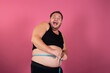 A funny fat man measures his waist in centimeters on a pink background. Sports, fitness and the process of losing weight.