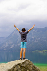 cute boy on the top of the rock in lake bohinj, slovenia