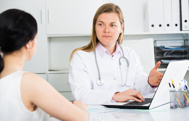 Female visitor consulting smiling woman doctor in hospital