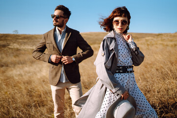 Young couple in love walking outdoors on a sunny day. The man gently hugs the woman. Love story. Autumn style.