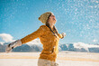 © cppzone - Young happy stylish girl whirls with raised hands and enjoys the snow in mountains. Winter holidays concept