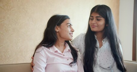 Wall Mural - A view of two south asian girls sitting on the couch and talking, enjoying each other's company in HD