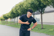 Male asian athlete, has chest pain fitness in the park and running, heart aches after cardio exercise
