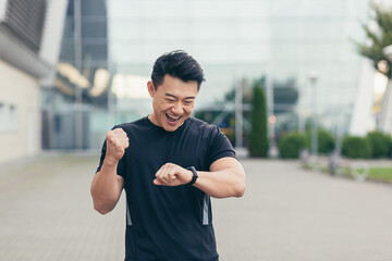 Male asian athlete on a morning run rejoices at the achieved result, smiles