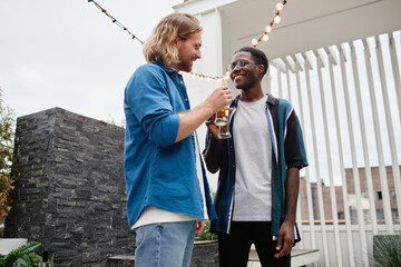 Poster - Waist up portrait of two young men chatting during outdoor party at rooftop, copy space