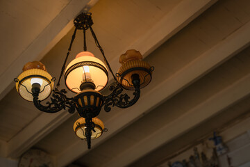 Antique metal frame chandelier lamp lighting bulbs hanging from the ceiling on dark background interior for home and living retro style building.