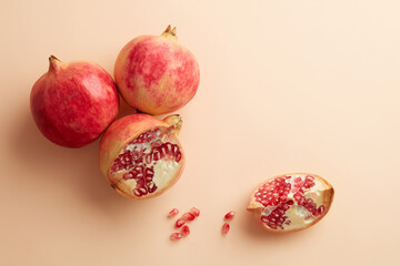 Wall Mural - Three red pomegranate fruit isolated on pastel beige background. Top view. Flat lay pattern