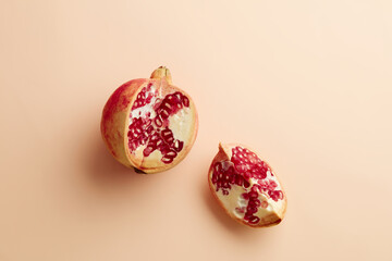 Wall Mural - Red pomegranate fruit and haff on pastel beige background. Top view