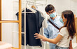 © Art_Photo - Young asian couple in quarantine for coronavirus wearing surgical mask face protection with social distancing shopping and choosing clothes at store.covid19 and new normal concept