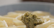 boiled penne pasta served with pesto sauce in blue bowl closeup
