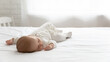 © fizkes - Sleepy silent few month infant resting in double bed with white sheet. Cute adorable peaceful baby in bodysuit sleeping in bedroom, lying on back on mattress. Childhood, child care, bedtime concept