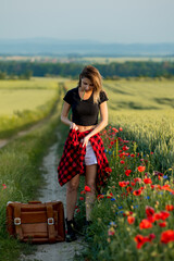 Sticker - Young woman with suitcase on countryside road in summer time