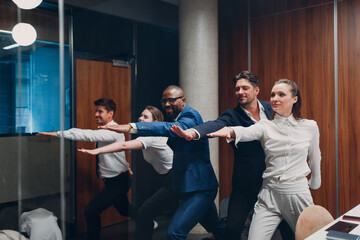 Businessman and businesswoman team doing warm up and yoga exercises before office meeting. Business healthy successful people group man and woman after conference discussion with boss.