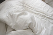 messy and crumpled  natural white bed sheets in bed
