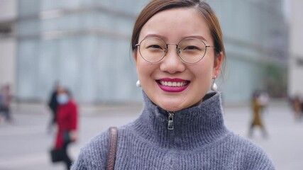 Wall Mural - 4k slow motion Portrait of an confidence Asian woman with glasses smiling at the camera in the street