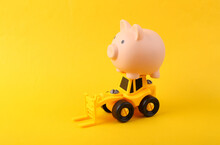 Toy Forklift With Piggy Bank On Yellow Background