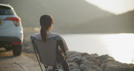 Poster - Woman sit on the camping chair and look at the sea