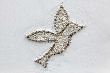 A bird laid out with small sea pebbles on the wall of the house