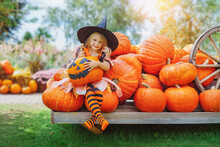 Child Girl Als Little Cute Witch With Pumpkin Outdoors In Halloween