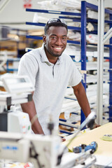 Portrait of young male worker assembling roller blind on production line in factory