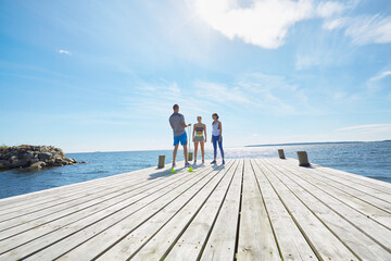 Mid distance view of friends wearing sports clothes standing on pier