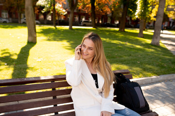 Wall Mural - Young scandinavian blonde woman talking on mobile while sitting on a