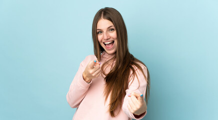 Sticker - Young caucasian woman isolated on blue background surprised and pointing front