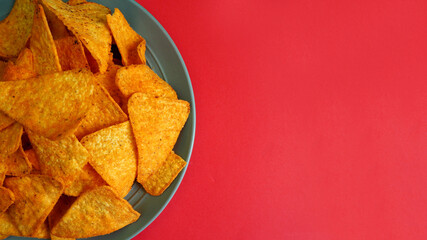 Wall Mural - close to the left, on a gray plate on a red background, there are many triangular corn tortilla chips. mexican cuisine. appetizer. top view