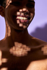 Wall Mural - Close-up verticale portrait of smiling male in shadow. Naked torso young man on purple background