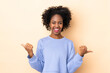 © luismolinero - Young African American woman isolated on beige background with thumbs up gesture and smiling