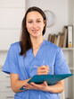 © JackF - Positive young female doctor working in a clinic takes important notes while standing in a well-lit office