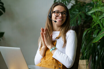 Wall Mural - Young woman small business owner in headset talk with client or partner using laptop computer and video call connection. Happy smiling gardener or florist pass online webinar courses on home gardening