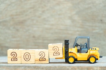 Sticker - Toy forklift hold letter block 2 to complete word 2022 on wood background