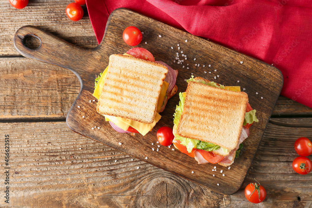 Board with tasty sandwiches on wooden background
