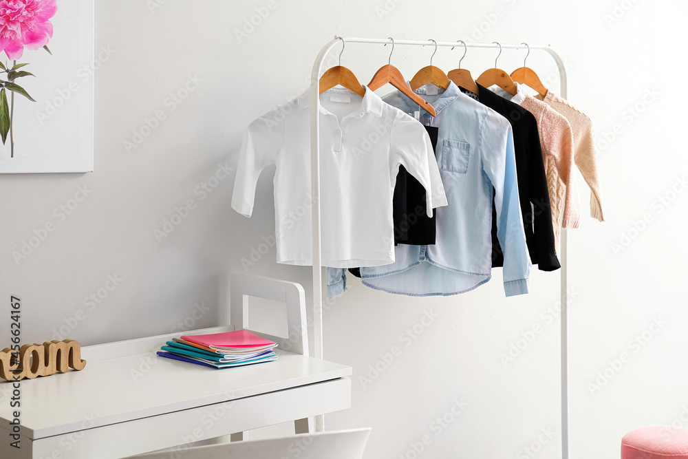 Workplace and rack with school uniform in interior of room